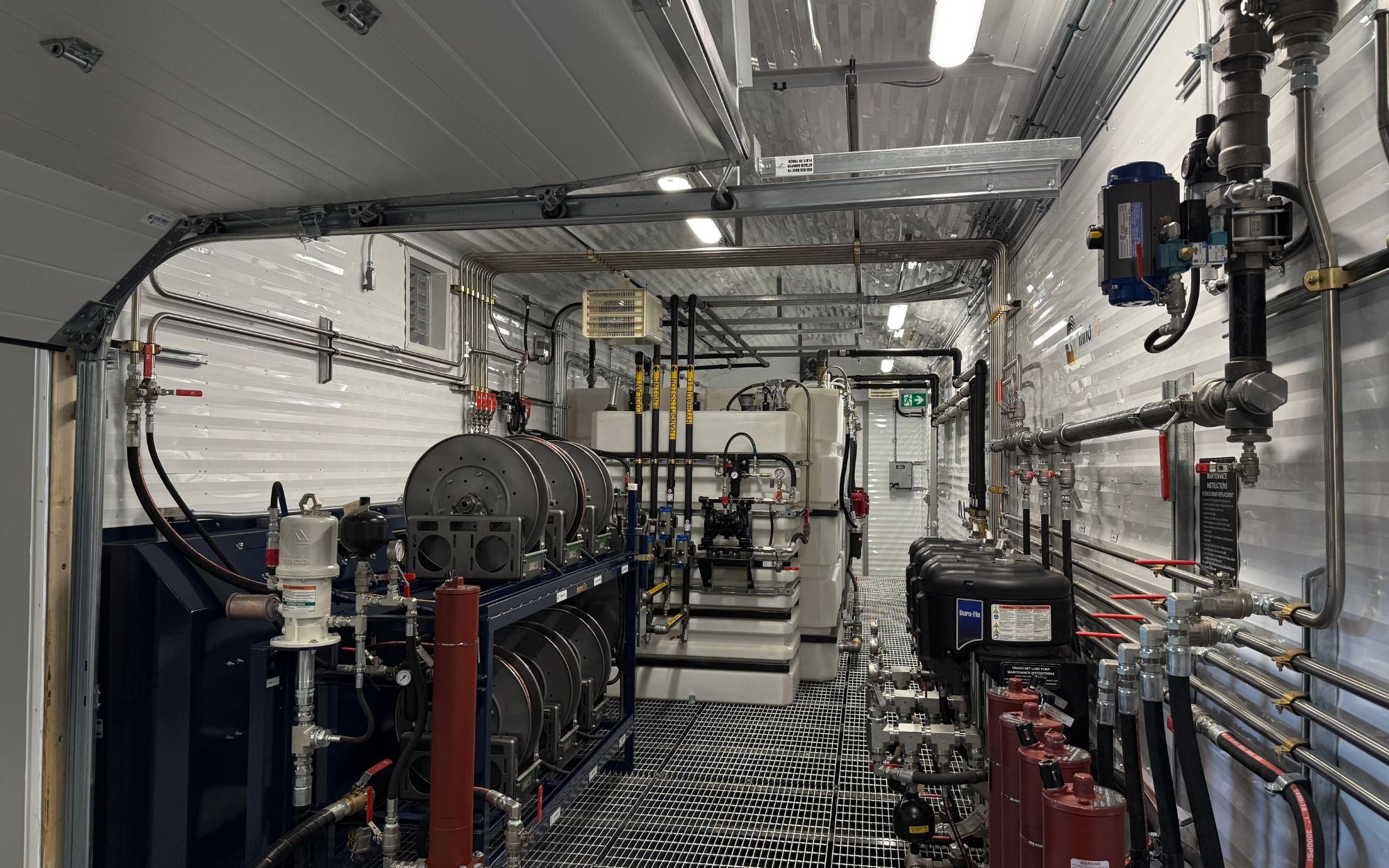 Interior of an Innoflo lube island showing hose reels, filter housings, stationary fluid storage tanks and overhead piping
