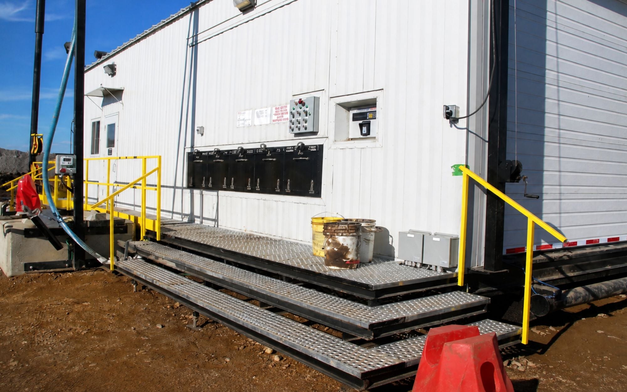 Exterior dispense bulkhead on an Innoflo lube island at a mine site, with a bank of dispense points above the access stairs